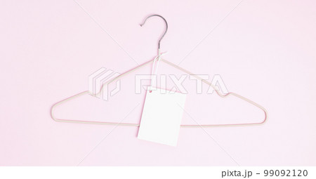 Creative flat lay hanger with white paper label pink background. Clothing tag, label blank mockup template. Sale discount store promo shopping concept. Top view. Copy space Creative flat lay hanger with white paper label pink background. Clothing tag, label blank mockup template. Sale discount store promo shopping concept. Top view. Copy space 99092120