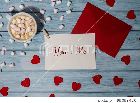 YOU plus ME text on valentine card inscription positive quote phrase Greeting card with red envelope with white cup of coffee and marshmallows on wooden background. Romantic Small hearts Valentine YOU plus ME text on valentine card inscription positive quote phrase Greeting card with red envelope with white cup of coffee and marshmallows on wooden background. Romantic Small hearts Valentine 99093420