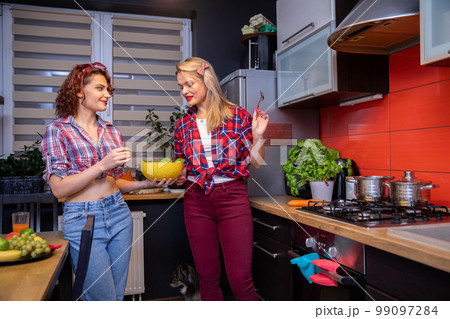 A brunette and a blonde prepare a healthy meal in the kitchen. 99097284