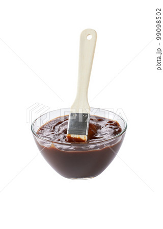 Barbecue sauce in a saucer with basting brush isolated on a white background. Bowl with barbecue sauce and brush. Barbecue sauce in a saucer with basting brush isolated on a white background. Bowl with barbecue sauce and brush. 99098502