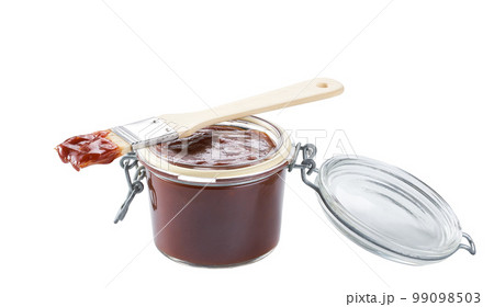 Barbecue sauce in a jar with barbecue brush isolated on a white background. Barbecue sauce in a jar with barbecue brush isolated on a white background. 99098503