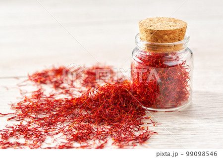 Dried saffron spices in a bottle on a wooden table, selective focus. 99098546