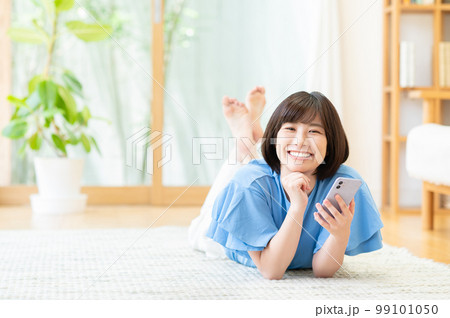 リビングでスマートフォンを使う若い女性 99101050