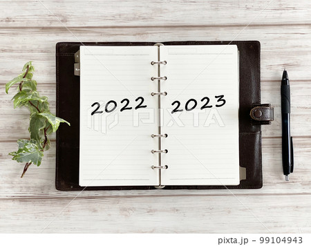 開いた手帳に2022と2023文字とボールペンとツタ_俯瞰 開いた手帳に2022と2023文字とボールペンとツタ_俯瞰 99104943