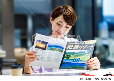 カフェで旅行のパンフレットを見る女性 撮影協力：WEEK芝大門(サンフロンティア不動産) 99105970