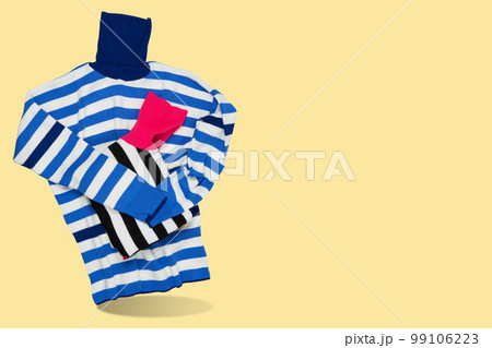 Women's sweater with high collar, blue and white stripes, as if holding a folded sweater, concept, on a yellow background Women's sweater with high collar, blue and white stripes, as if holding a folded sweater, concept, on a yellow background 99106223