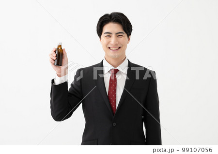 栄養ドリンクを持つビジネスマン 栄養ドリンクを持つビジネスマン 99107056