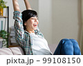 ソファでストレッチをする若い女性　リラックス　休憩　リフレッシュ　体操 99108150