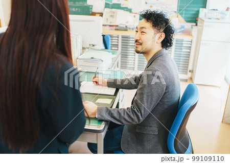 職員室で生徒の相談を受ける先生 99109110
