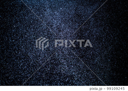 Organic dust particles floating on a colorful light beam on black background. 99109245