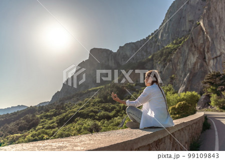 Profile of a woman doing yoga in the top of a cliff in the mount 99109843