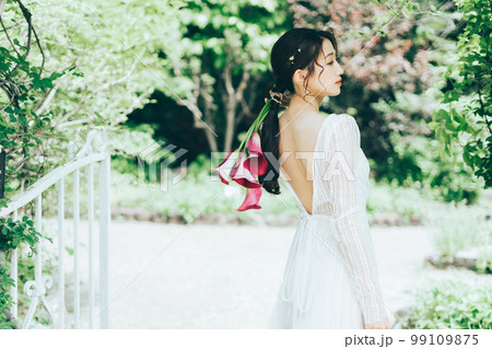 カラーのブーケを持つウェディングドレスの女性 99109875