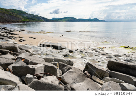 Famous Lyme Regis beach, world heritage site in Dorset, South West England. View of stones and liffs and blue sea. The beach is full of fossils. Selective focus 99110947