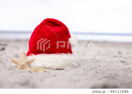Santa Claus hat and starfish on the sandy beach Santa Claus hat and starfish on the sandy beach 99112886