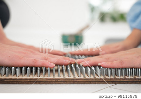 Close-up of two women's hands on sadhu boards. Nailing practice. 99115979