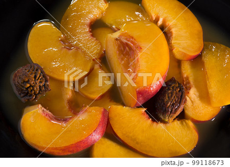 Juicy ripe peaches in own juice. Close up. On a black background 99118673