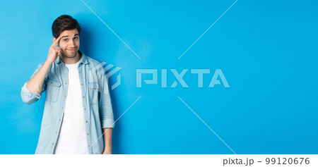 Young thoughtful man pointing at head, asking to think about it, giving a hint, standing in casual clothes over blue background Young thoughtful man pointing at head, asking to think about it, giving a hint, standing in casual clothes over blue background 99120676