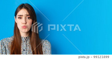 People emotions concept. Sad cute girl begging for something, pucker lips and frowning, whining asking please, standing on blue background 99121899