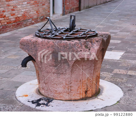 Old water well with iron grille in Venice, Italy. Street scene, old brick 99122880
