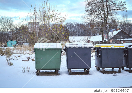 Green and grey plastic dumpster waste and garbage containers on wheels on thin snow in winter season Green and grey plastic dumpster waste and garbage containers on wheels on thin snow in winter season 99124407