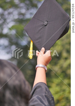 Student hold hats in hand during commencement success on yellow background Student hold hats in hand during commencement success on yellow background 99124594