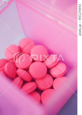 close up of pink color medical pills in a pill box on table  99124943
