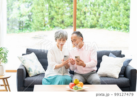 リビングでスマホを持つシニア夫婦 99127479