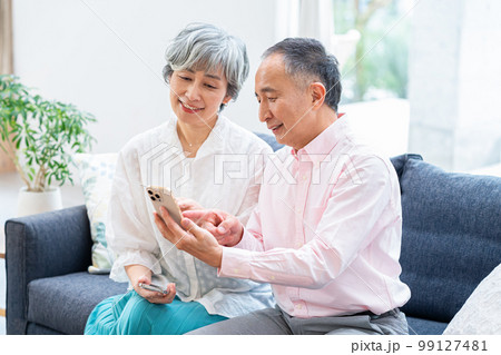 リビングでスマホを持つシニア夫婦 99127481
