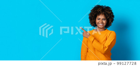 Pretty african american young woman pointing at empty space Pretty african american young woman pointing at empty space 99127728