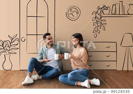 Loving middle eastern couple sitting on floor, drinking tea 99128330