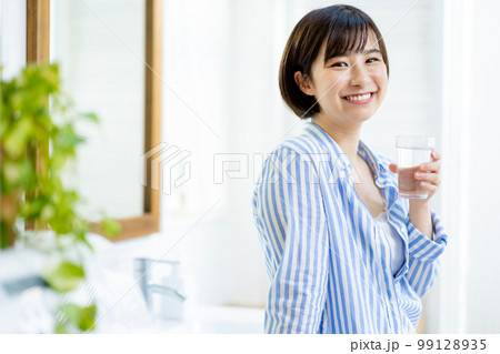 若い女性が水が入っているコップを持つ 若い女性が水が入っているコップを持つ 99128935