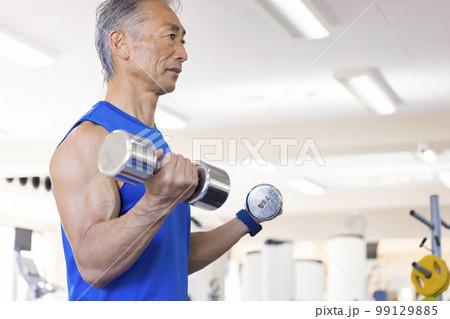フィットネスジムでダンベルカールをする中高年男性 フィットネスジムでダンベルカールをする中高年男性 99129885