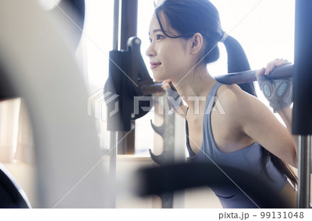 フィットネスジムでバーベルスクワットをする若い女性 99131048
