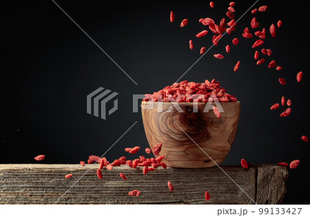 Dried goji berries are poured into a wooden bowl. Dried goji berries are poured into a wooden bowl. 99133427
