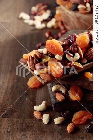 Mix of nuts and dried fruits on an old wooden table. 99133437