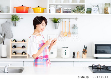 キッチンでスマホを使うミドルの主婦 99134013