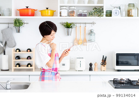 キッチンでスマホを使うミドルの主婦 99134014