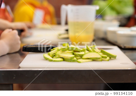 Cooking a dish in a culinary studio. Sliced vegetables on a cutting board and sauce in a measuring cup. Selective focus. Cooking a dish in a culinary studio. Sliced vegetables on a cutting board and sauce in a measuring cup. Selective focus. 99134110