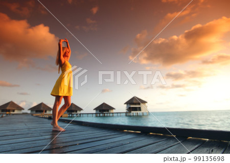 woman in a dress on maldivian sunset 99135698