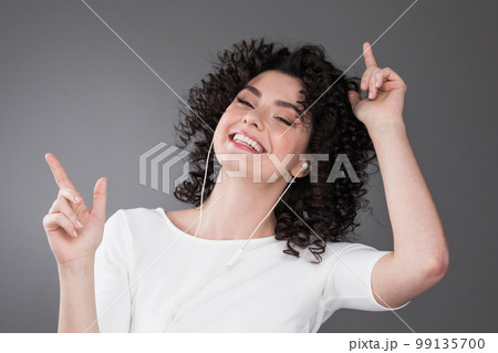 Young woman listening music in earphones 99135700