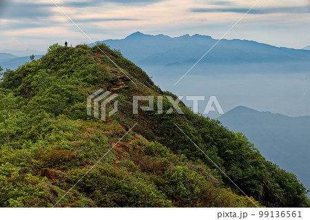 早朝の谷川岳・西黒尾根を行く登山者と上州武尊山の山並み 99136561