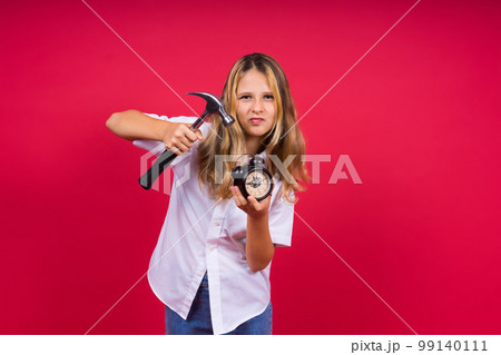 Kid girl holding hammer and alarm clock smiling with a happy and cool smile on face. showing teeth. 99140111