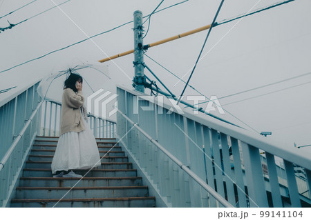 陸橋に傘をさしてスマホを持っている女性の写真 99141104