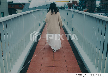 陸橋に傘をさしてスマホを持っている女性の写真 99141106