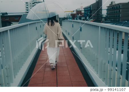 陸橋に傘をさしてスマホを持っている女性の写真 99141107