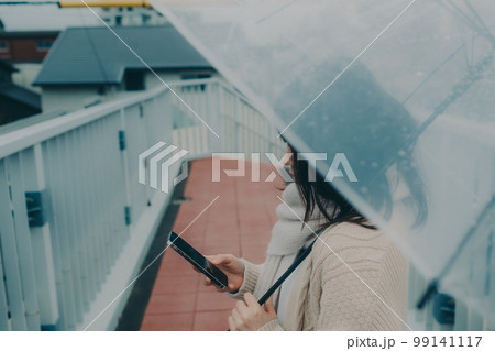 陸橋に傘をさしてスマホを持っている女性の写真 陸橋に傘をさしてスマホを持っている女性の写真 99141117