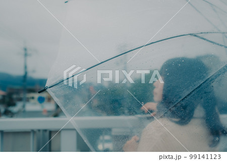 陸橋に傘をさしてスマホを持っている女性の写真 99141123