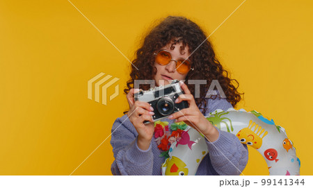 Happy young woman tourist photographer taking photos on retro camera and smiling, holiday vacation Happy young woman tourist photographer taking photos on retro camera and smiling, holiday vacation 99141344