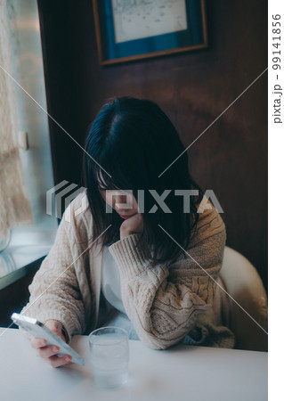 喫茶店でスマホをさわる女性の写真 喫茶店でスマホをさわる女性の写真 99141856
