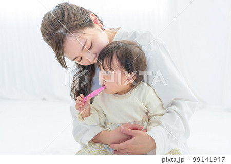 赤ちゃんの歯磨きを身守る母親 99141947